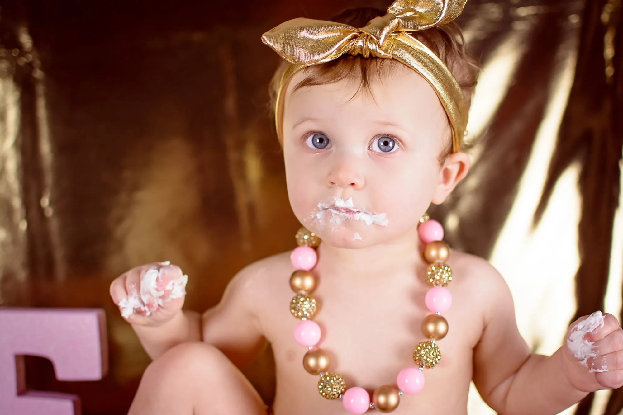 Cake smash photos in the Cedar Valley, birthday girl with a gold bow