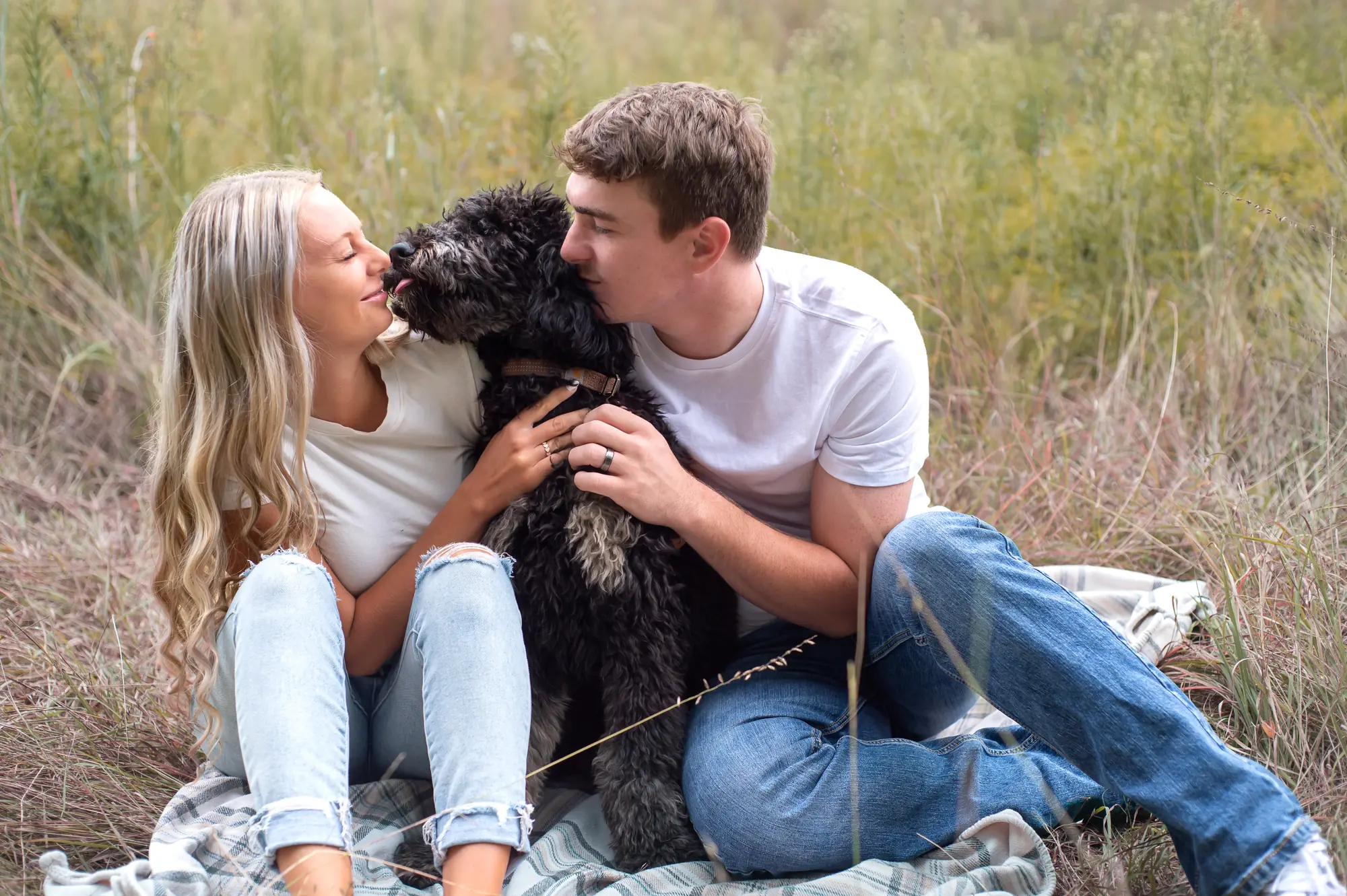 Engagement photos in the Cedar Valley, couple cuddling their dog in a field