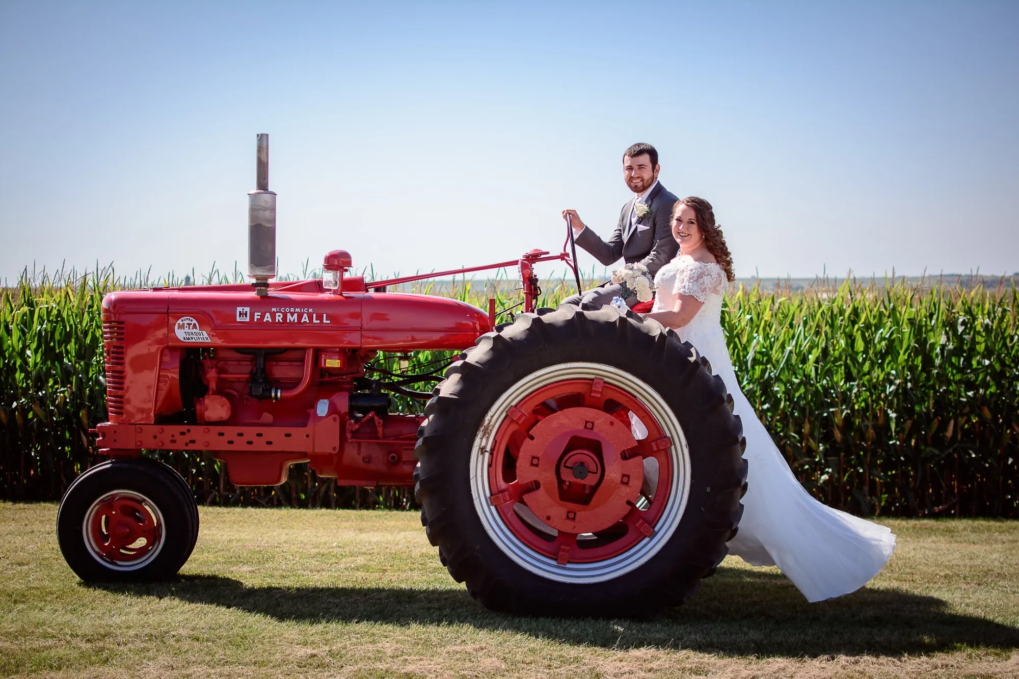 Farm wedding photos in the Cedar Valley, bride and groom on a red Farmall tractor