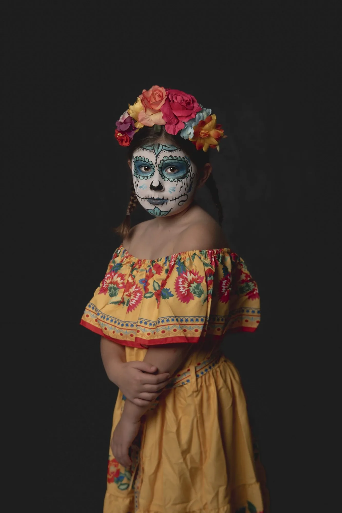 Girl in blue sugar skull makeup and a yellow ruffled dress posing for a Halloween costume portrait in Cedar Falls, Iowa