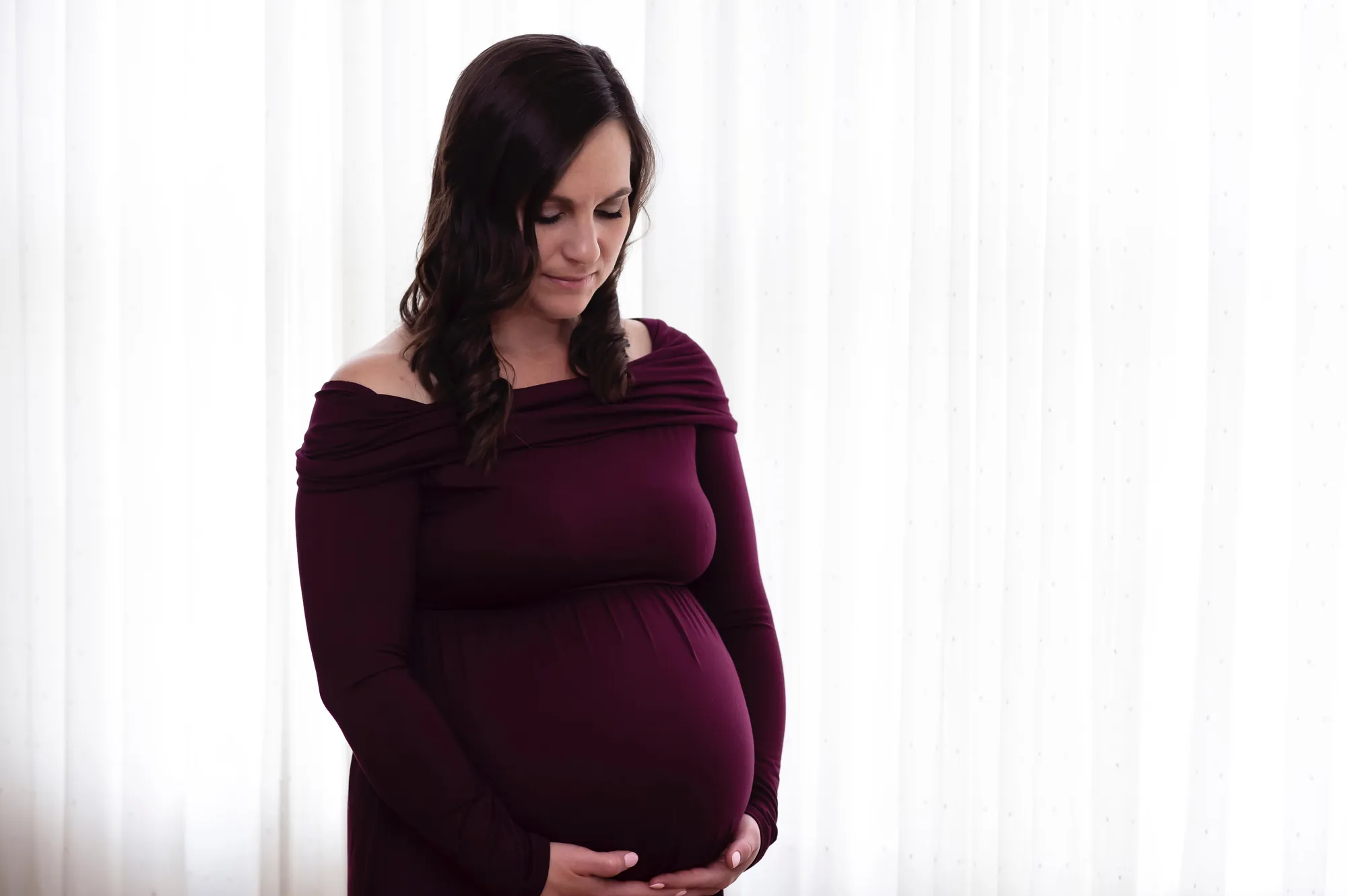 Maternity photos in the Cedar Valley, soft window light in a burgundy gown