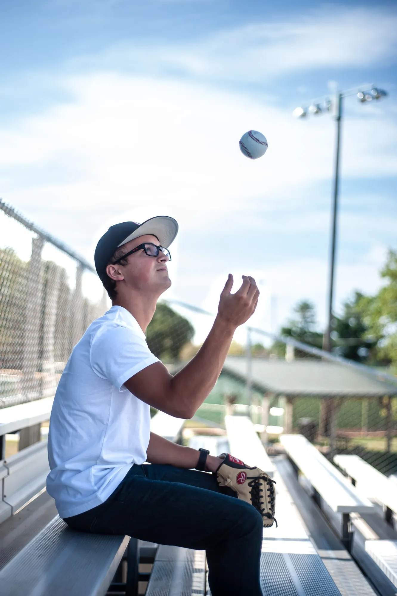Senior pictures in the Cedar Valley, baseball player tossing a ball on the bleachers