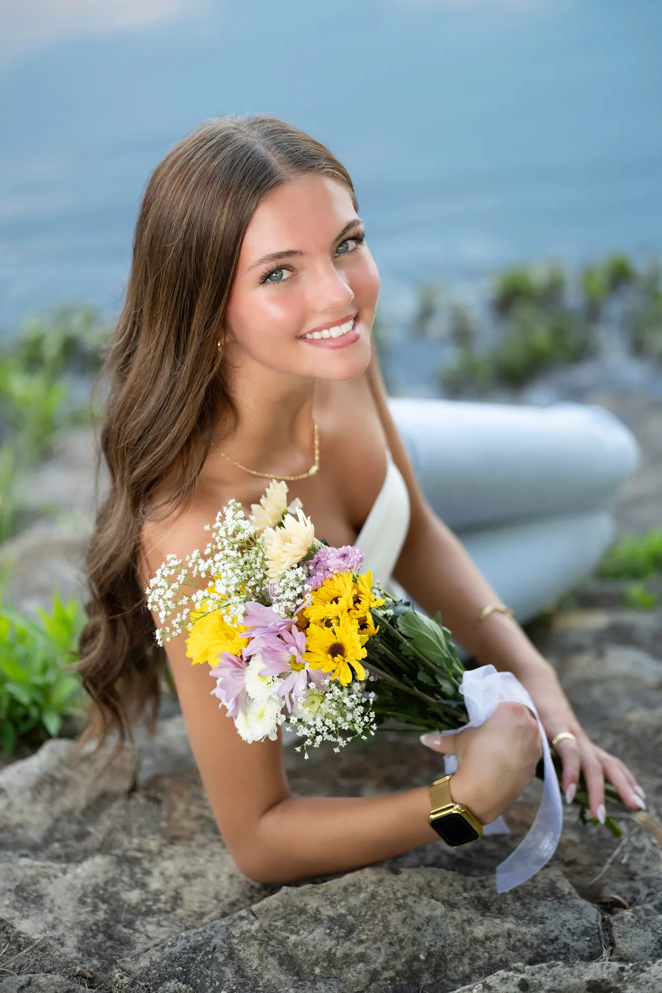 Senior pictures in the Cedar Valley, smiling with a bouquet on the rocks