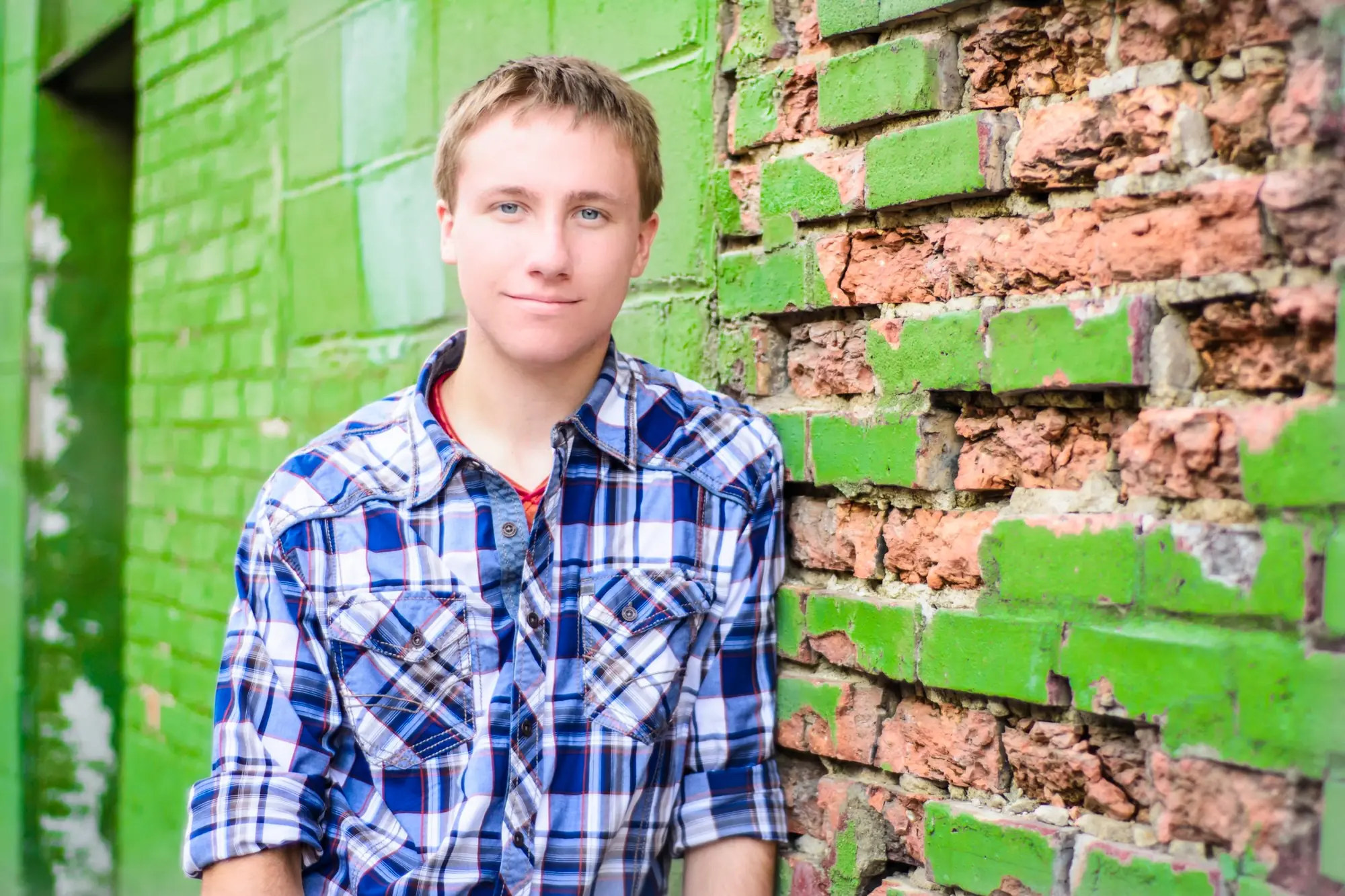 Senior pictures in downtown Cedar Falls, Iowa against a green painted brick wall.