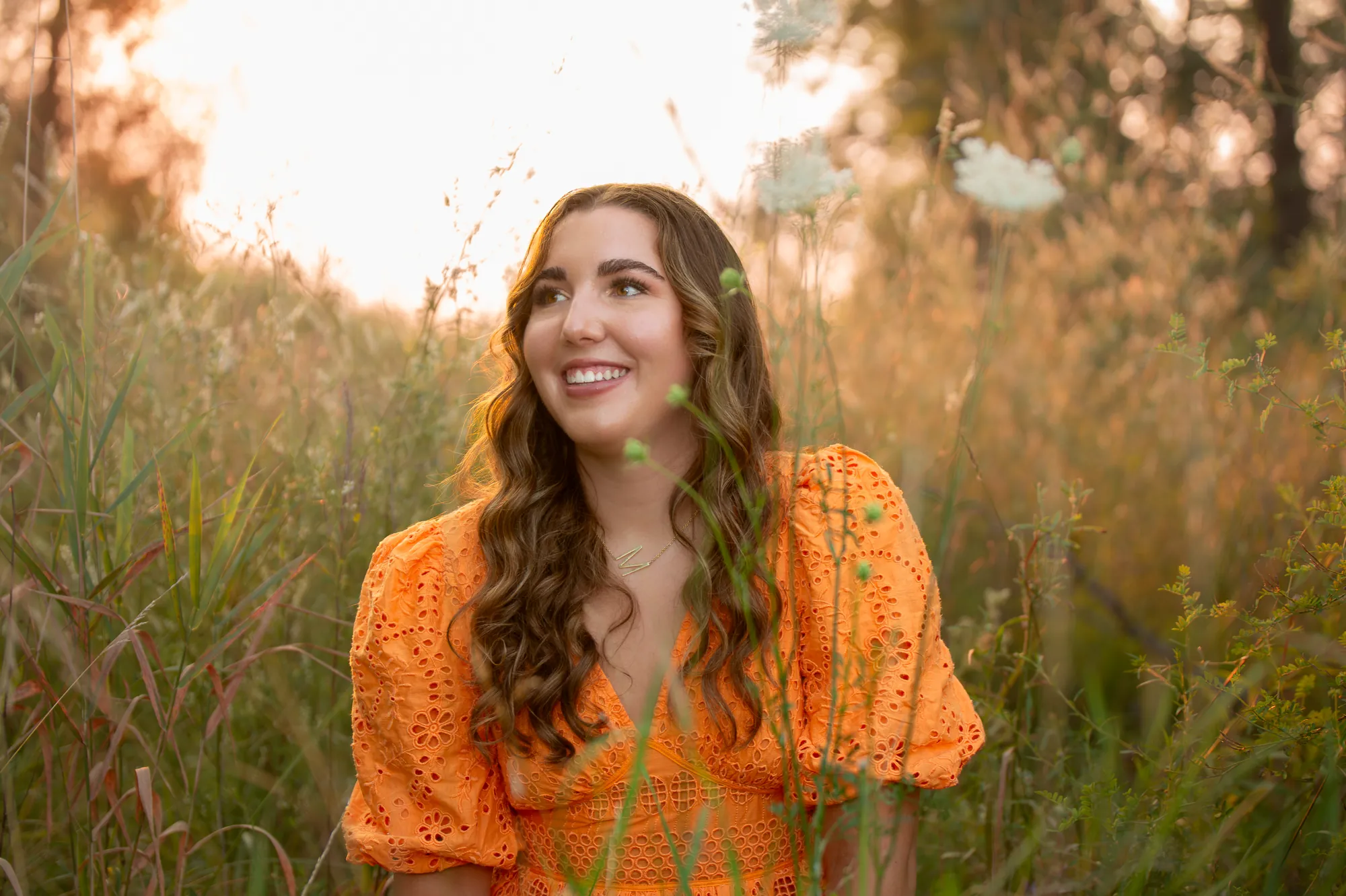 Senior pictures in the Cedar Valley, orange dress in tall grass at golden hour