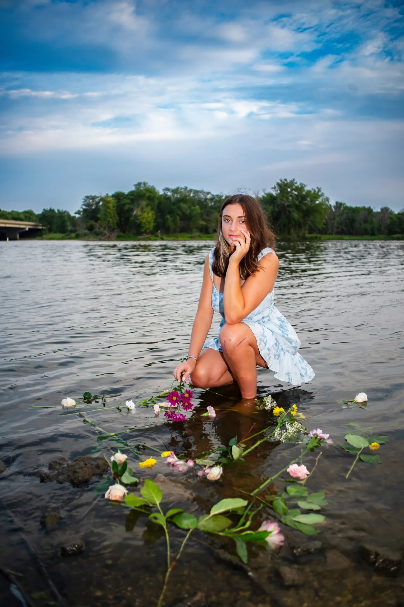 Senior pictures in the Cedar Valley, kneeling in the Cedar River with flowers
