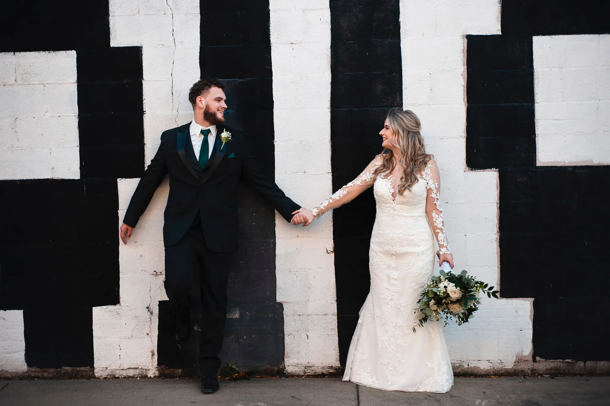 Wedding photography in Waterloo, bride and groom holding hands by a black and white mural