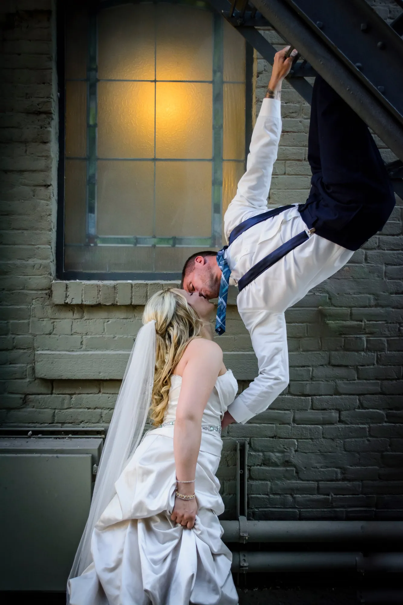 Fun wedding photos in the Cedar Valley, upside-down kiss outside a brick building