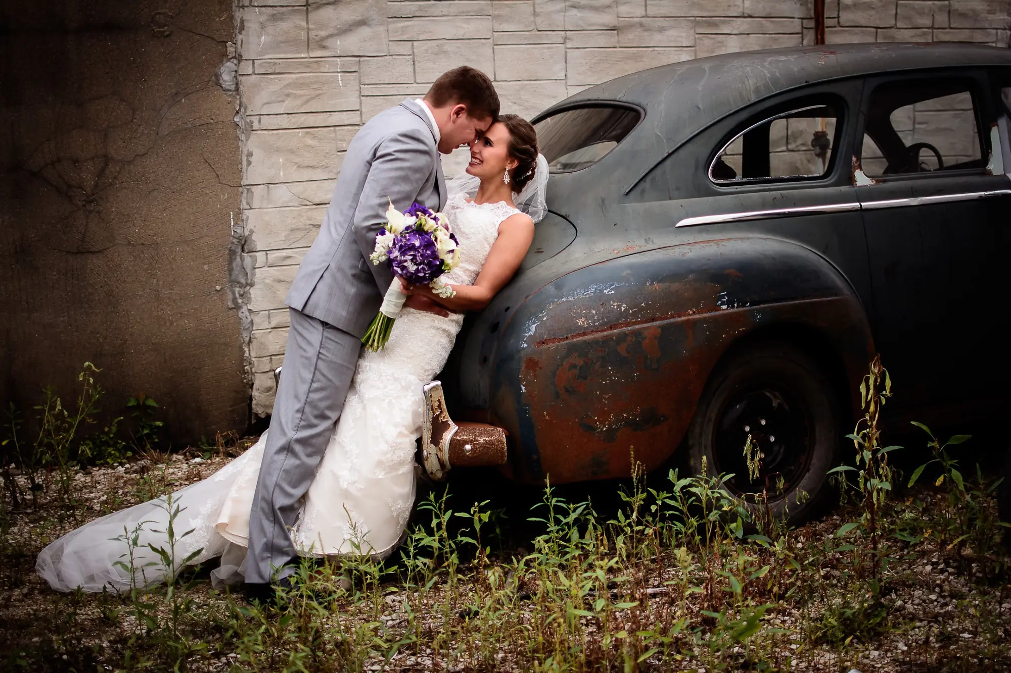 Wedding photos in the Cedar Valley, couple by a vintage car with a purple bouquet