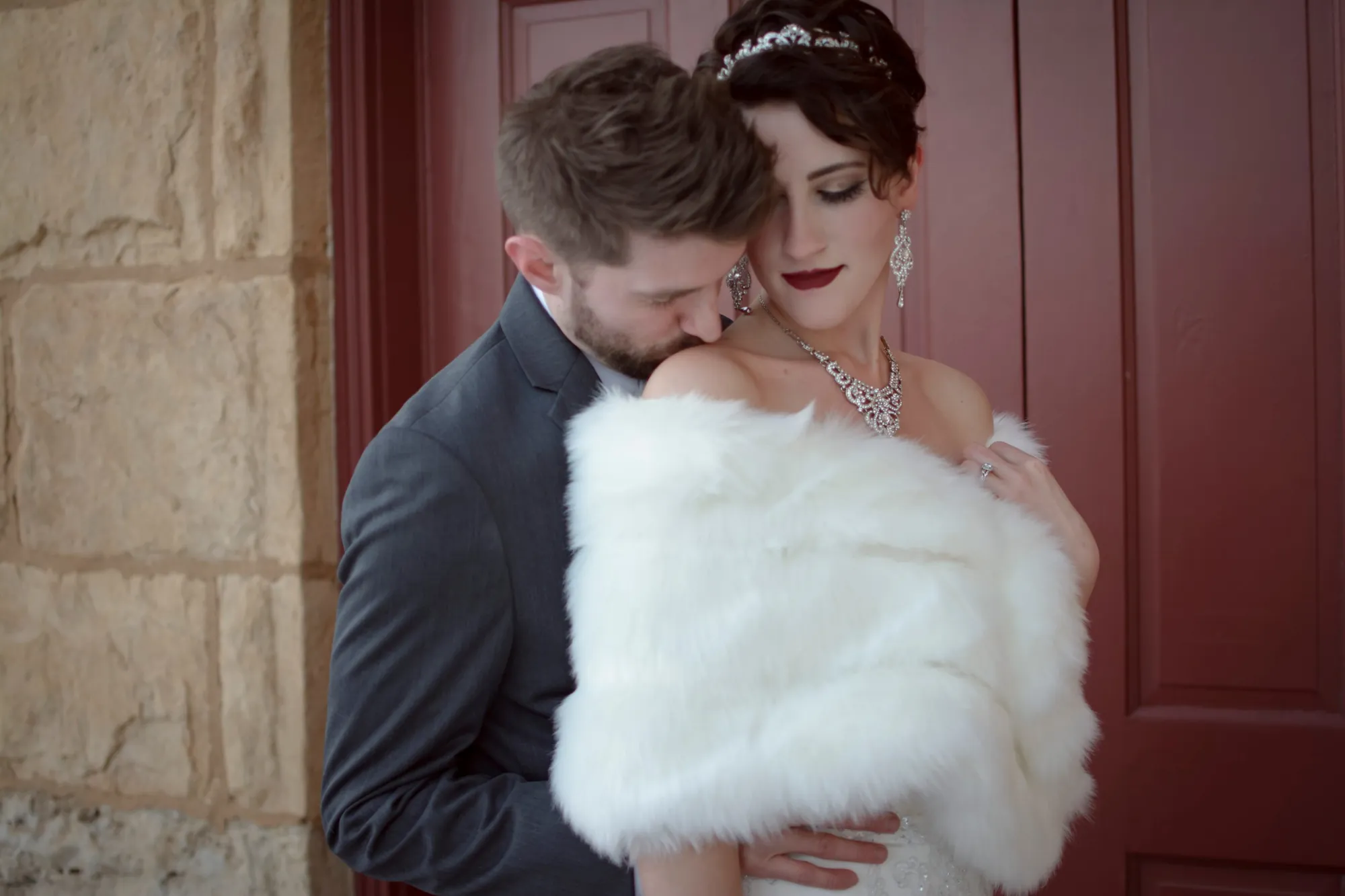 Winter wedding photography in the Cedar Valley, bride in a fur wrap by a red door